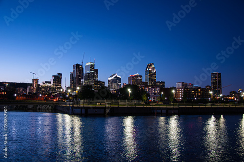 Montreal's skyline at night, a symphony of lights reflecting off the water under a deep blue sky, encapsulates urban elegance.