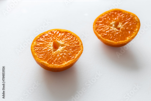 juicy orange tangerine cut in half with white background.