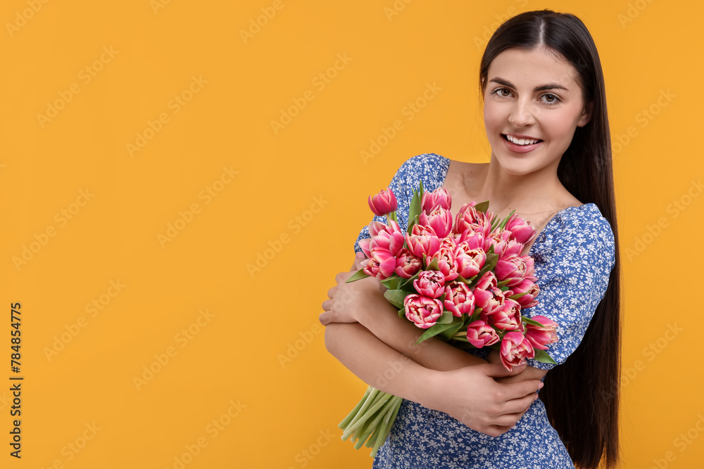 Happy young woman with beautiful bouquet on orange background. Space for text
