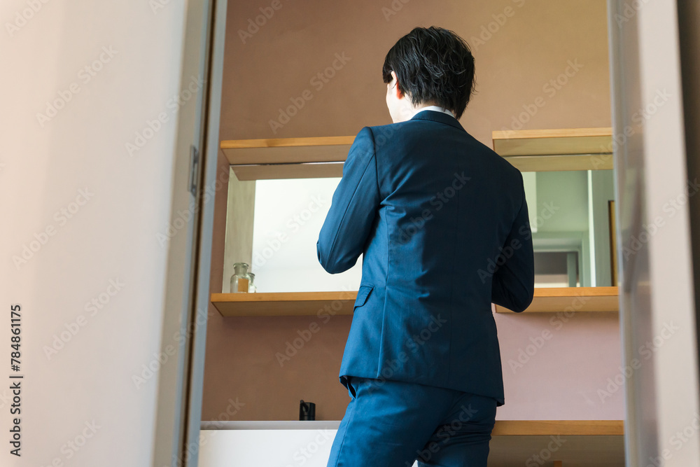 洗面所で身支度するスーツ姿の若い男性ビジネスマン

