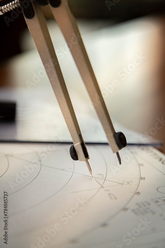 Closeup of a navigator's radar plotting chart with a triangler and compass divider and a calculated angle