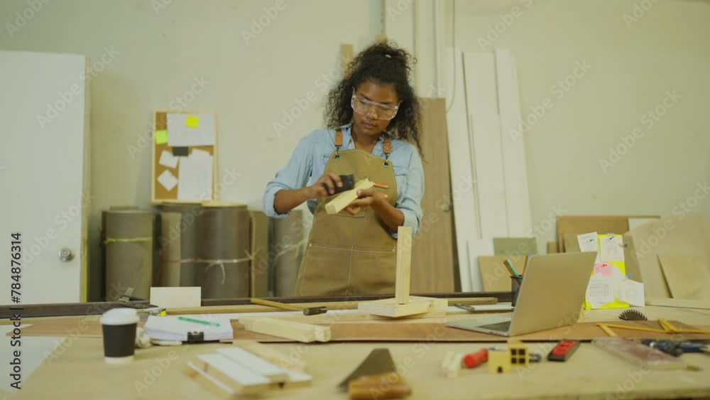 Professional carpenter or woodworker or charpentier woman use sandpaper to scrub wooden stick to prepare for producing wood work in workplace.