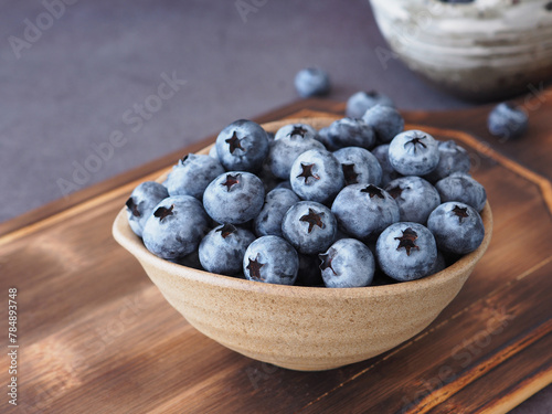 Fresh blueberries in oval brown bowl on cutting board. Blueberry antioxidant organic superfood, Close up with copy space. Concept for healthy eating and nutrition..