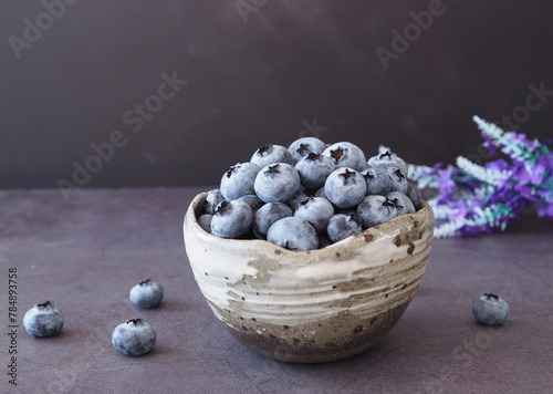 Organic ripe fresh blueberries in bowl on dark grey stone background. Concept for healthy eating and nutrition, space for your text. Superfood..
