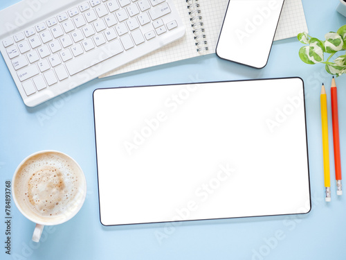 Top view, flat lay template, mock-up digital tablet pc computer with blank white screen and coffee cup, smartphone, keyboard, pencil on blue workplace..Business, technology concept..