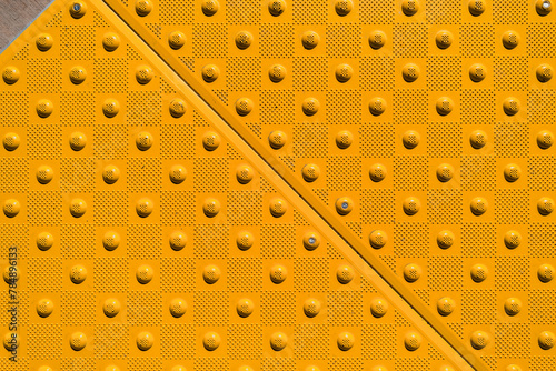 Close up detail of a yellow ADA warning pad on a concrete sidewalk