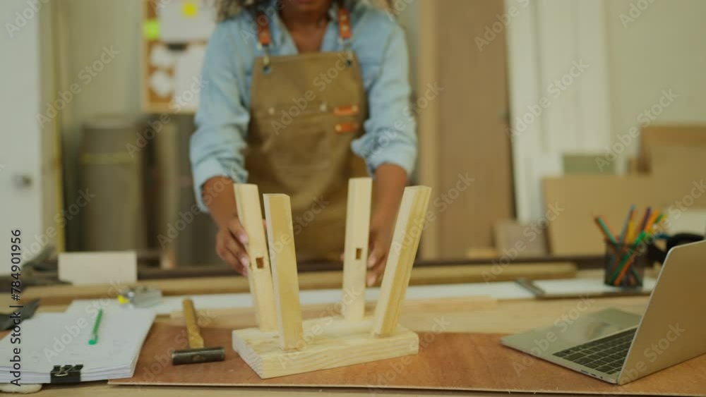 Professional carpenter or woodworker or charpentier woman assemble wooden stick to the wooden product as small chair in workplace.