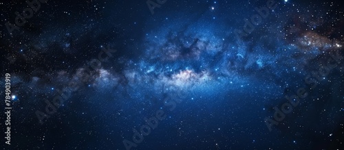 A serene night sky with a deep blue hue scattered with numerous stars and a striking bright blue center