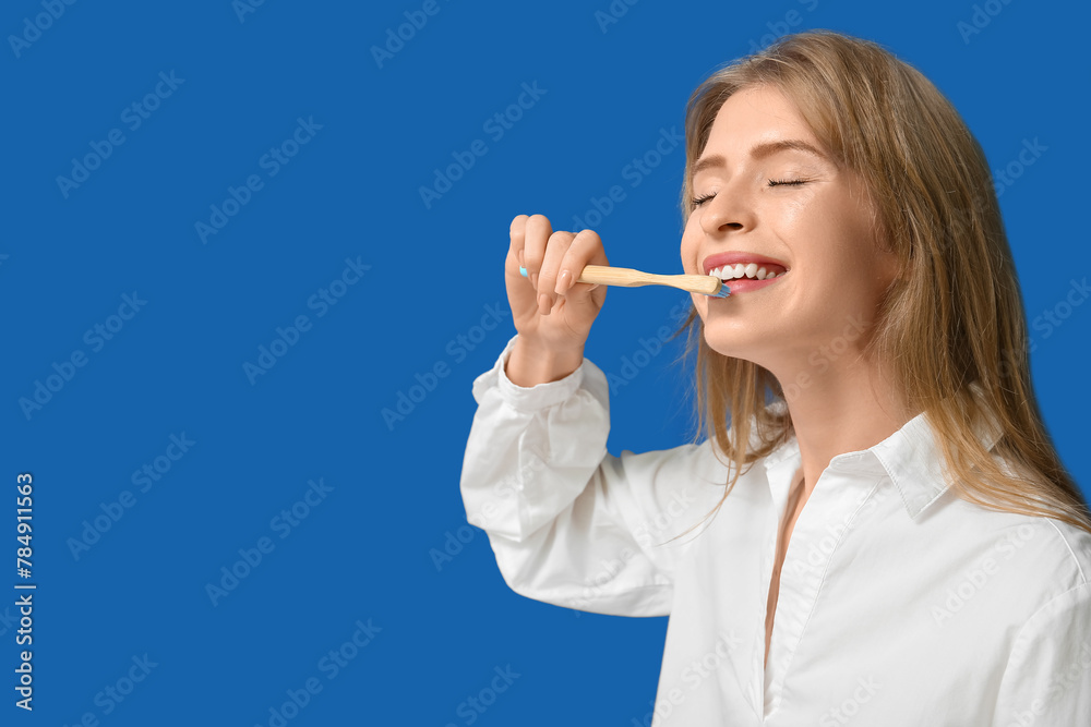 Young woman brushing her teeth on blue background Young woman brushing her teeth on blue background
