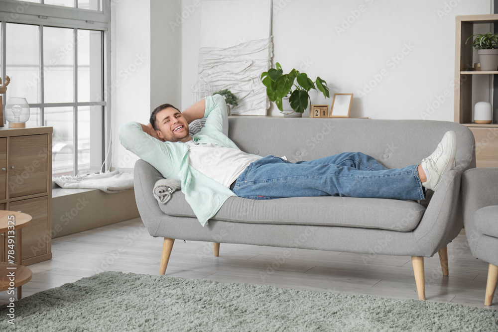 Young man lying on grey sofa at home Young man lying on grey sofa at home