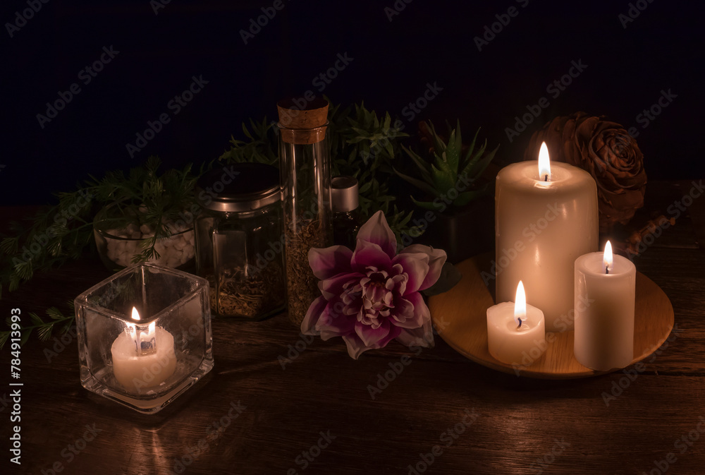 lit candles and decorative objects with plants, herbs, flowers in a dark environment lit candles and decorative objects with plants, herbs, flowers in a dark environment