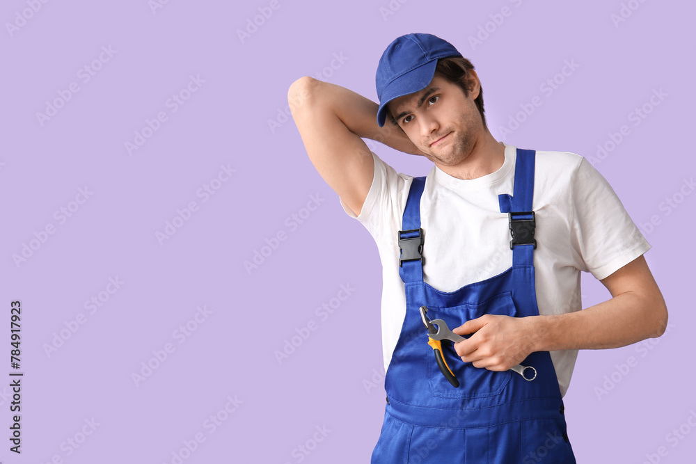 Tired male worker with wrench on lilac background - obrazy, fototapety, plakaty 