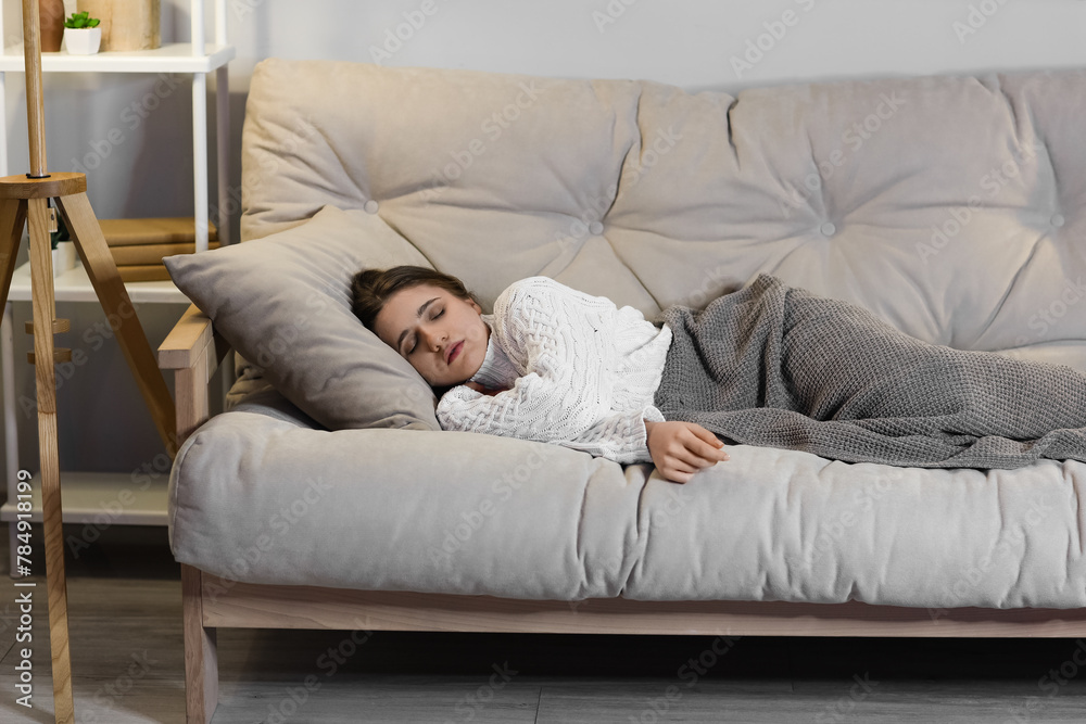 Young woman sleeping on sofa at home in evening