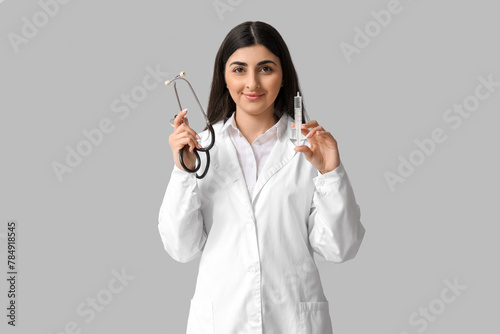 Bild auf Leinwand Beautiful young female doctor with syringe and stethoscope on white background