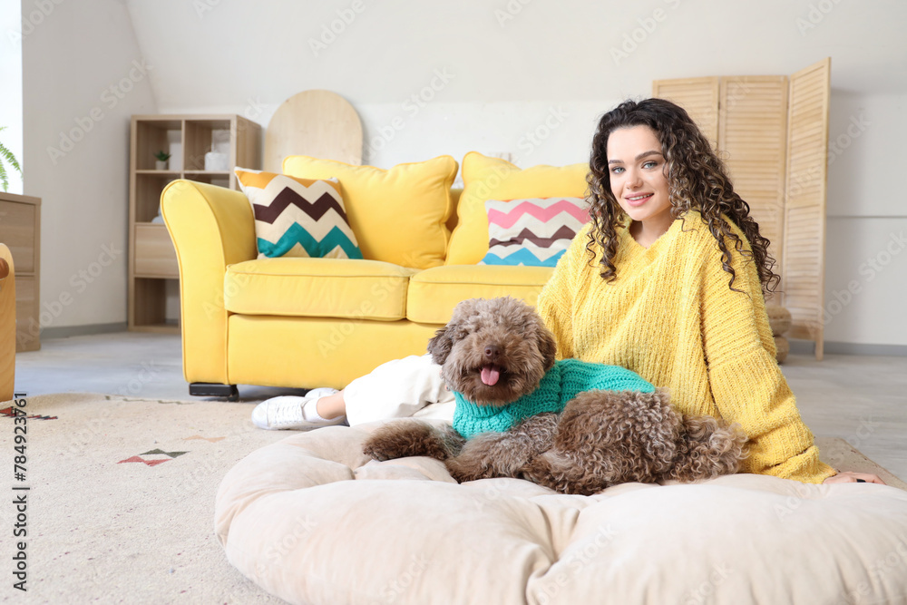 Young woman with cute poodle sitting on pet bed at home Young woman with cute poodle sitting on pet bed at home
