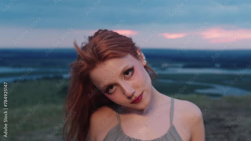 red-haired woman with freckles and bright makeup is dancing in nature, wearing a green dress. She looks at the camera. Medium shot. Slow motion. red-haired woman with freckles and bright makeup is dancing in nature, wearing a green dress. She looks at the camera. Medium shot. Slow motion.