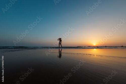 silhouette of a woman walking along the beach. Meditation of the spiritual world. Happy girl walks along the beach against the backdrop of sunset.