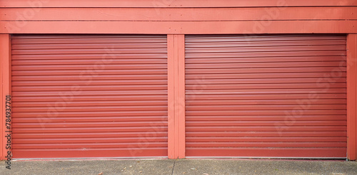 two single rust color garage doors corrugated metal against red wall © Angela