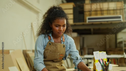Professional carpenter or woodworker or charpentier woman check wood product on table then look at camera with smiling in workplace.