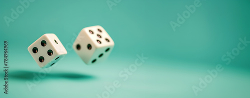 Two white dice in mid-air against a teal background with ample copy space.