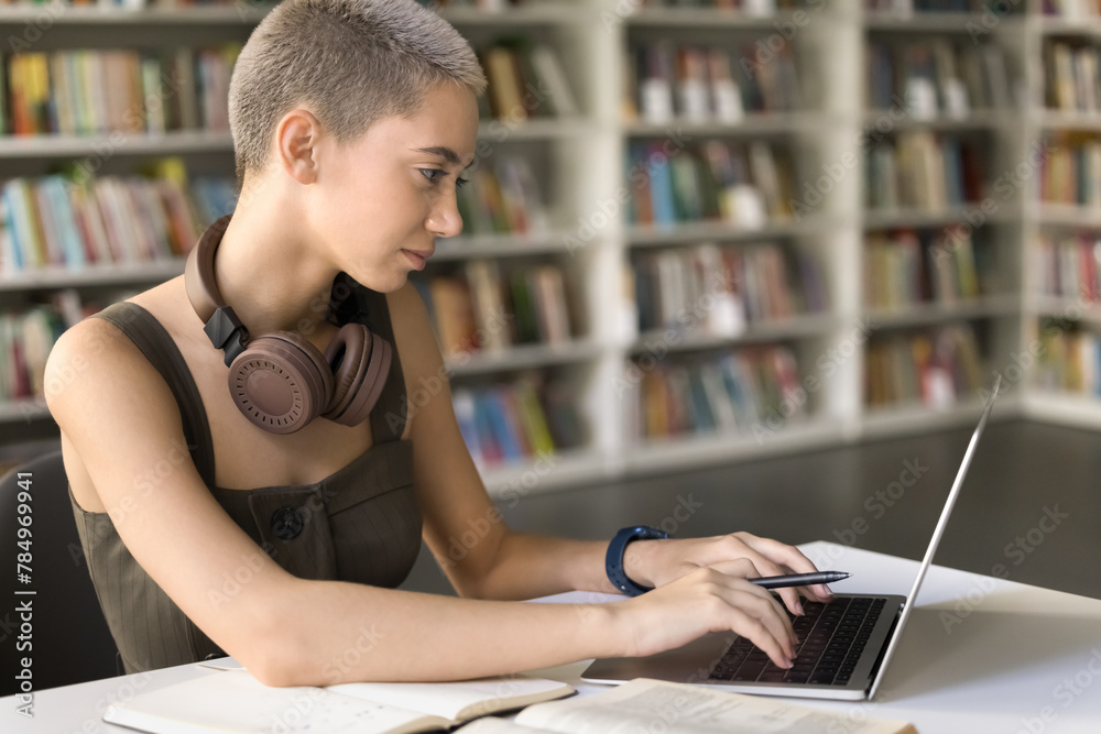 Short haired student girl studying in university library typing on laptop keyboard, prepare essay, making summary, working on thesis using modern tech, search information on internet for schoolwork Short haired student girl studying in university library typing on laptop keyboard, prepare essay, making summary, working on thesis using modern tech, search information on internet for schoolwork