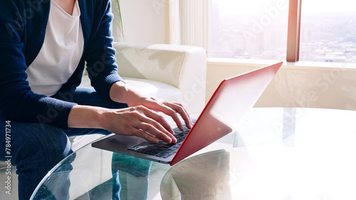 A woman sitting on a sofa and using a laptop computer.