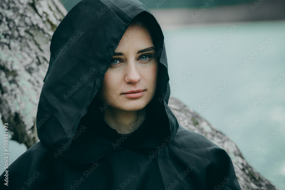 Woman in linden alley in dark clothes with long hair on blurred natural background Woman in linden alley in dark clothes with long hair on blurred natural background