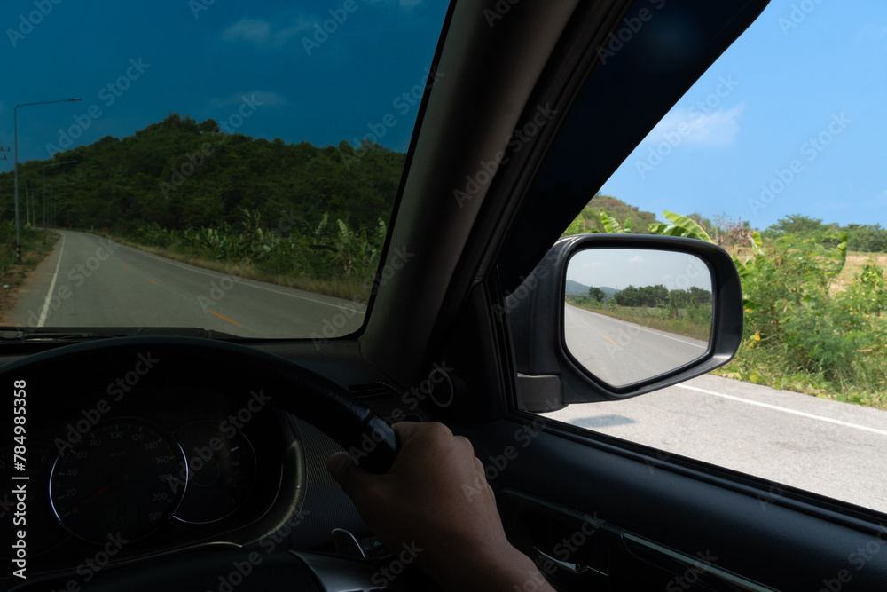 View from the inside of a car. View from the driver's seat. Driving on the asphalt road with nature of tree and mountain beside road. Under blue sky in the day time. View from the inside of a car. View from the driver's seat. Driving on the asphalt road with nature of tree and mountain beside road. Under blue sky in the day time.