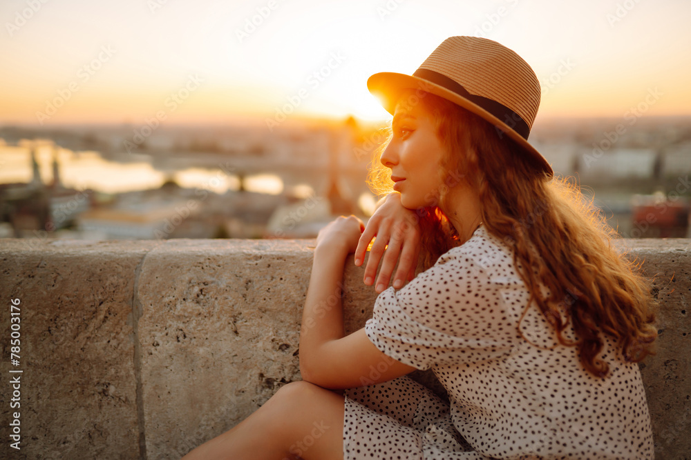 Portrait of female tourist looking at panoramic view of the city at sunset. Lifestyle, travel, tourism, nature, active life.