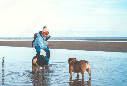 Happy woman tourist with English bulldogs dogs hiking and exploring new places on coastline 