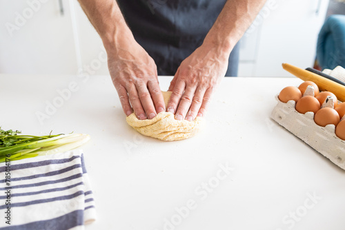 Man's hands kneading dough on the table in the kitchen