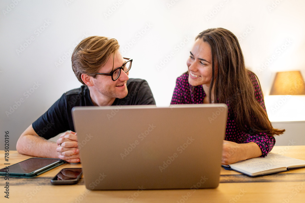 Caucasian man and Aboriginal woman sitting together at a table in an office looking at a laptop Caucasian man and Aboriginal woman sitting together at a table in an office looking at a laptop