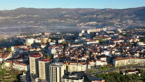 Picturesque drone view of Vila Real cityscape in valley framed by Serra do Alvao and Serras do Marao mountains in light fog on sunny spring day, Portugal  photo