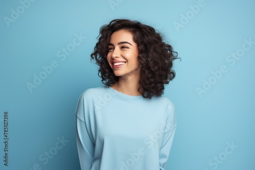 A woman with curly hair is smiling and wearing a blue shirt