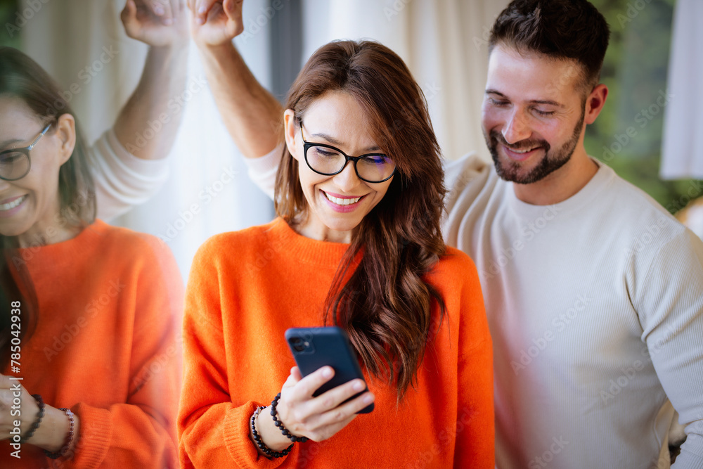 Woman and man standing at the window at home and using a smartphone Woman and man standing at the window at home and using a smartphone