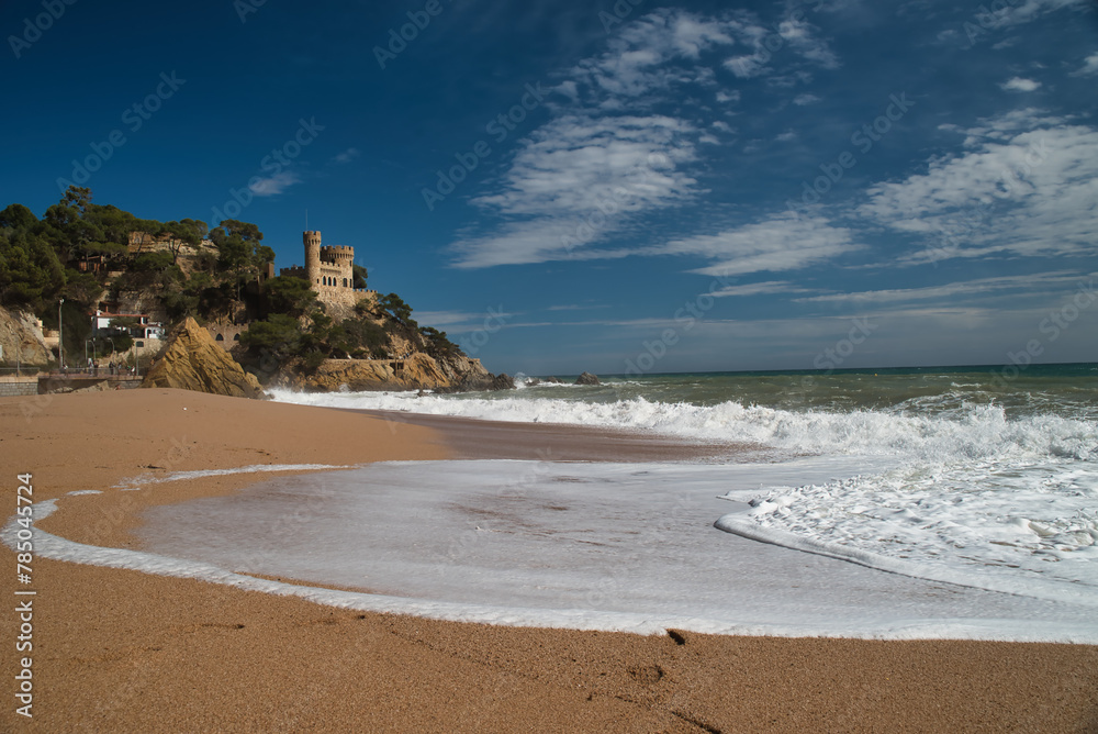 Lloret de Mar Castell on the beach, with a strong swell and white waves that reach the inside of the beach, leaving a trail of foam and sand. Costa daurada, Catalonia Spain. Photo taken in winter.