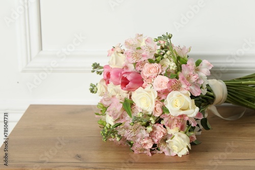 Beautiful bouquet of fresh flowers on wooden table near white wall © New Africa