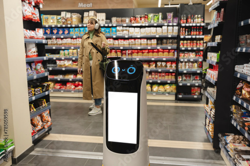 Smart delivery robot near grocery racks with woman in background at supermarket photo