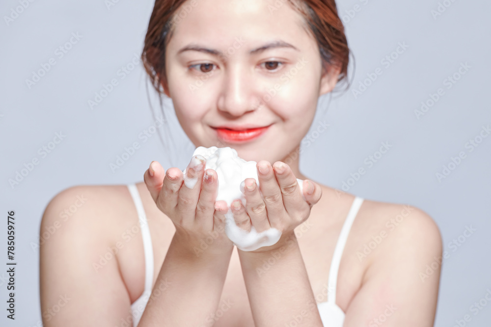 Smiling young woman washing foam face by natural foamy gel. satisfied girl with bare shoulders applying cleansing beauty product on cheeks. personal hygiene, skincare daily routine. Smiling young woman washing foam face by natural foamy gel. satisfied girl with bare shoulders applying cleansing beauty product on cheeks. personal hygiene, skincare daily routine.