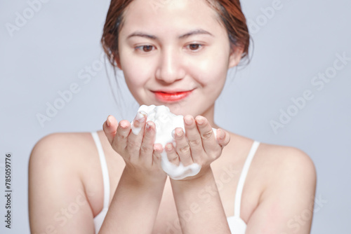 Smiling young woman washing foam face by natural foamy gel. satisfied girl with bare shoulders applying cleansing beauty product on cheeks. personal hygiene  skincare daily routine.