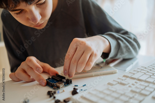 Teenage boy adjusting electrical component near keyboard at home