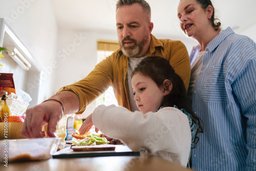 Father and mother with daughter preparing sandwich at home photo