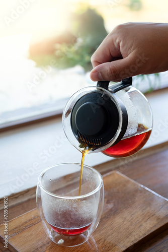 Hand pouring hot coffee into beautiful glass