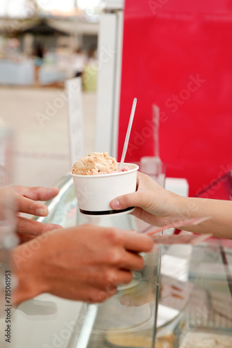 Hand serving ice-cream cup to the hand of customer