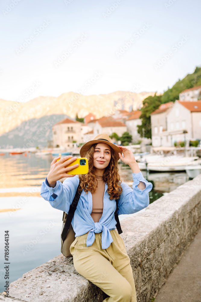 Young female tourist is exploring new city making photo on smartphone. Selfie time. Lifestyle, adventure, nature, active life.