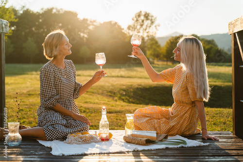 Friends with wineglasses sitting in park on vacation