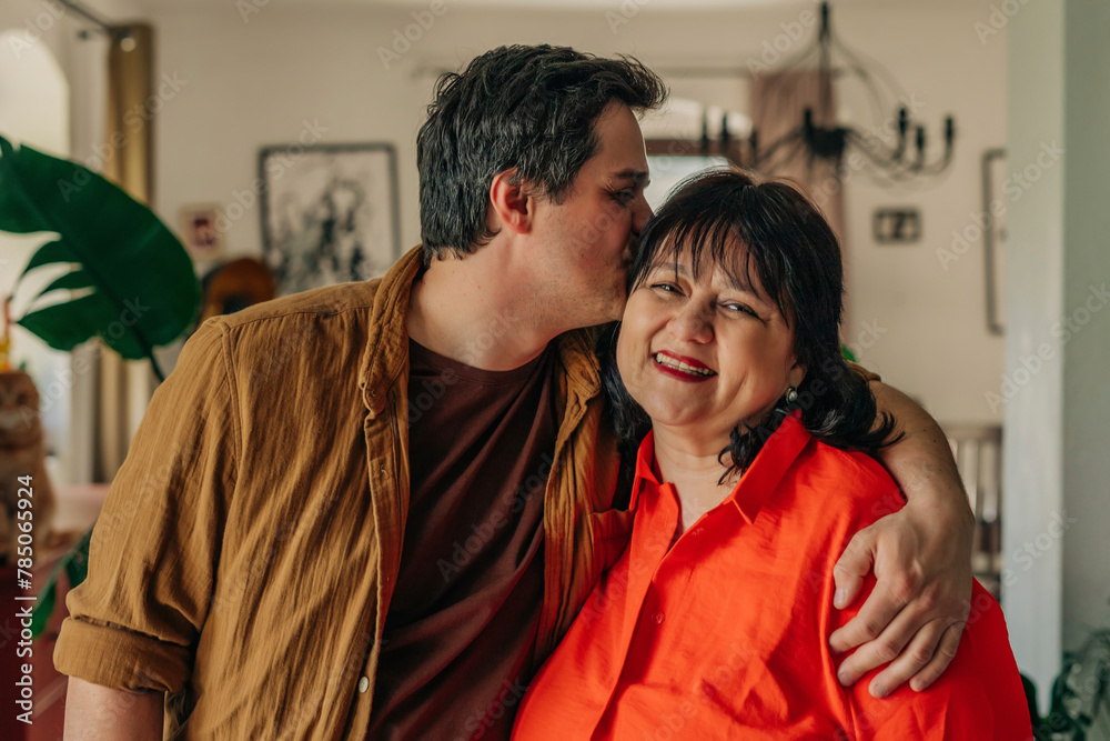 Man kissing mother on head at home Man kissing mother on head at home