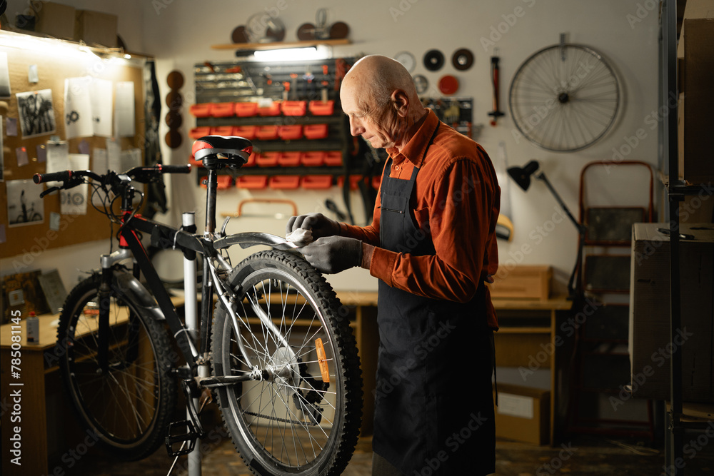 Old man cleaning mountain bike in garage or repair workshop. Bicycle Maintenance