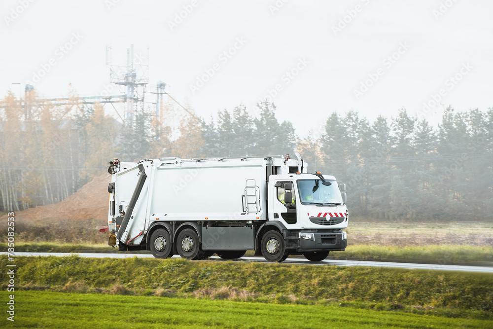 Isolated modern waste truck on the road. Sanitation industry. Municipal waste management
