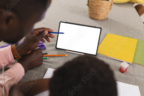 Father and son, both African American, focusing on tablet with copy space and doing homework